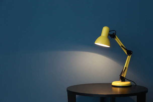 Lámpara moderna en mesa cerca de la pared de color - Foto, Imagen