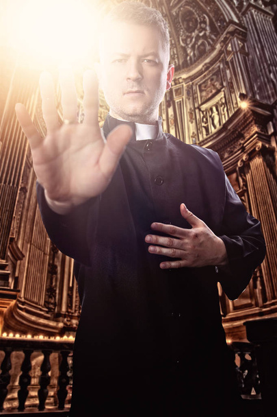 priester met een uitgestoken hand aan de kerk - Foto, afbeelding
