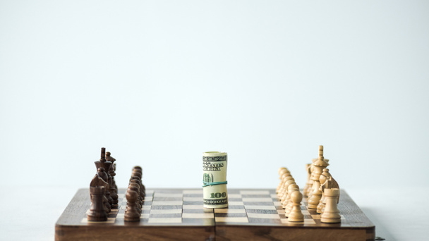 Schachbrett mit Bargeld und Schachfiguren isoliert auf Weiß - Foto, Bild