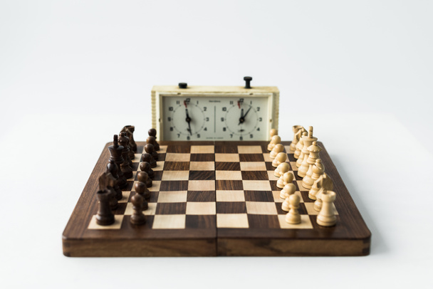 Reloj y tablero de ajedrez con piezas de ajedrez aisladas en blanco
 - Foto, Imagen
