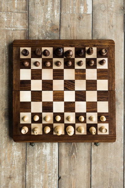 Top view of chess board with chess pieces set for new game on wooden surface - Photo, Image