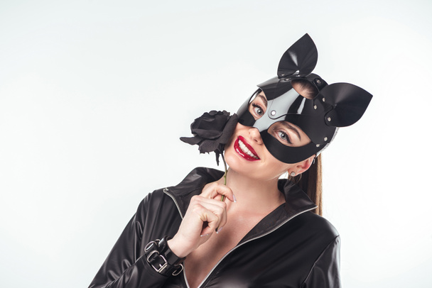 Attractive hot girl in mask smiling and holding black rose isolated on white - Foto, afbeelding