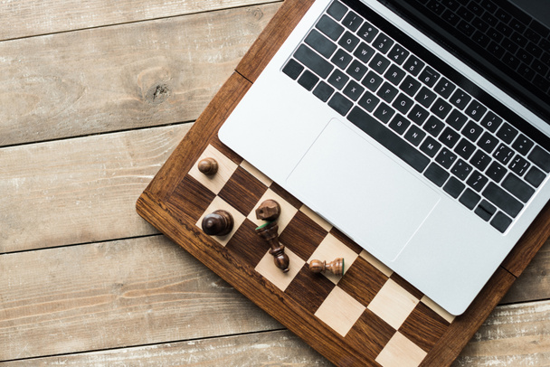 Bestuur, laptop en Schaken schaakstukken op rustieke houten oppervlak (bovenaanzicht) - Foto, afbeelding