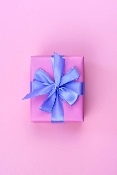 Caja de regalo festiva decorativa con color rosa sobre fondo rosa. lazo de cinta de satén lila
. - Foto, imagen