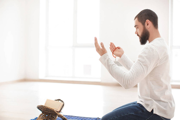 Young Muslim man praying, indoors - Foto, afbeelding
