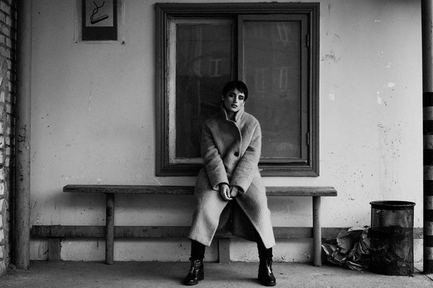 Black and white photo of beautiful young woman in fashionable coat posing  - Valokuva, kuva