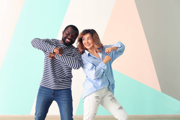 Cute interracial couple dancing against color wall - Фото, зображення