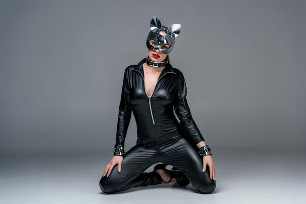 Kinky γυναίκα με σέξι κοστούμι και μάσκα σε γκρίζο φόντο - Φωτογραφία, εικόνα