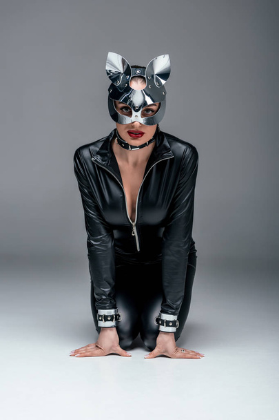 Странная женщина в сексуальном костюме и маске сидит в покорном положении
 - Фото, изображение