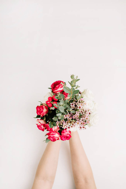 Woman hands hold bouquet of roses, eucalyptus branch, wildflowers. Flat lay, top view spring background. - 写真・画像