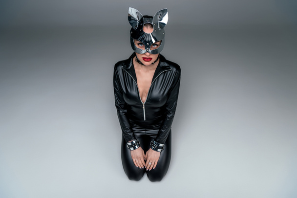 Seductive young woman in mask sitting in submissive position - Foto, afbeelding