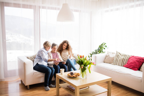 A teenage girl, mother and grandmother with tablet at home. - 写真・画像