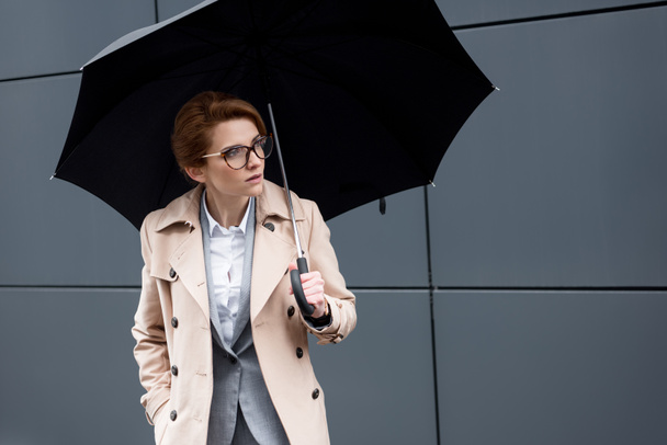 portrait of businesswoman in stylish coat with umbrella on street - Fotoğraf, Görsel