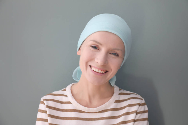 Young woman with cancer in headscarf on grey background - Фото, зображення