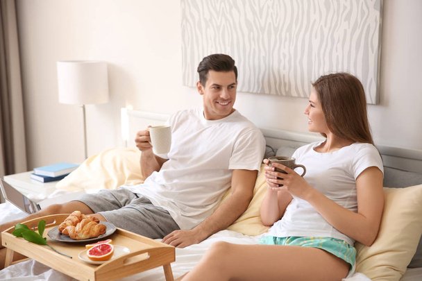 Young couple having breakfast on bed at home - Foto, Imagen