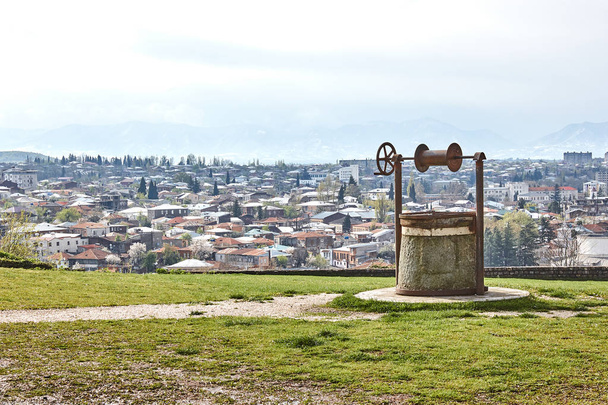 Retro old well on the background of the city panorama. Kutaisi, Georgia. - Photo, Image