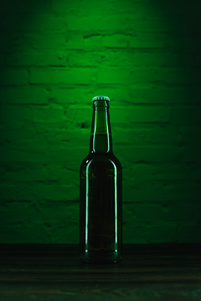 zbliżenie jednego zielone piwo butelka w zielone światło - Zdjęcie, obraz