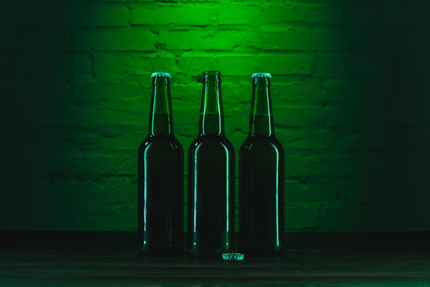 tres botellas de cerveza verde cerca de la pared de ladrillo verde
 - Foto, imagen