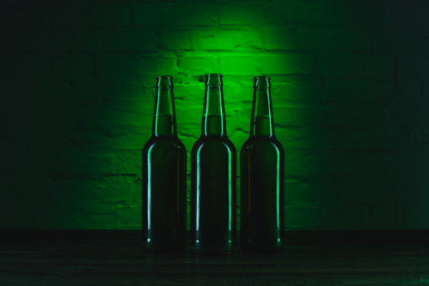 three open green beer bottles in green light - Photo, Image
