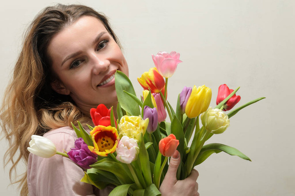 Young charming girl with a bouquet of flowers - multi-colored tulips - Photo, image