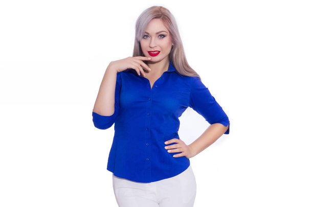 Studio business portrait of a young blonde woman in a dark blue shirt and white trousers. Girl posing on isolated white background. Smiling, looking at the camera - 写真・画像