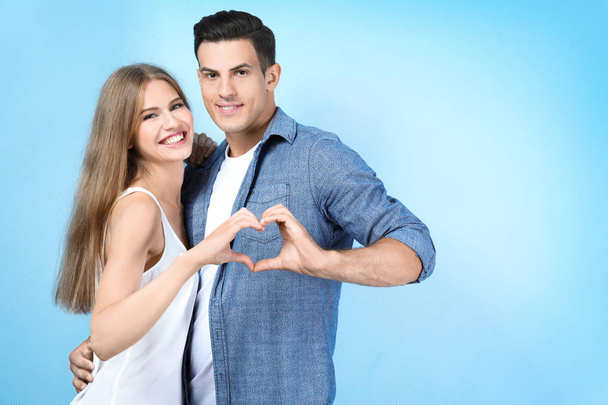 Young couple holding hands in shape of heart on light background - Fotó, kép