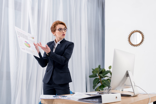 businesswoman pointing at documents while talking with colleague at workplace in office - Φωτογραφία, εικόνα
