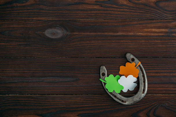 vista superior de herradura y tréboles en colores de bandera irlandesa sobre mesa de madera
 - Foto, Imagen