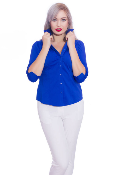 Studio business portrait of a young blonde woman in a dark blue shirt and white trousers. Girl posing on isolated white background. Smiling, looking at the camera - Fotó, kép