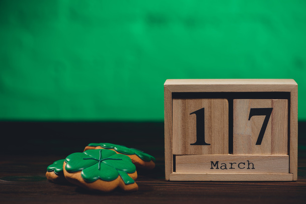 close-up view of calendar with 17 march date and cookies and hsape of shamrocks on wooden table top - Photo, Image