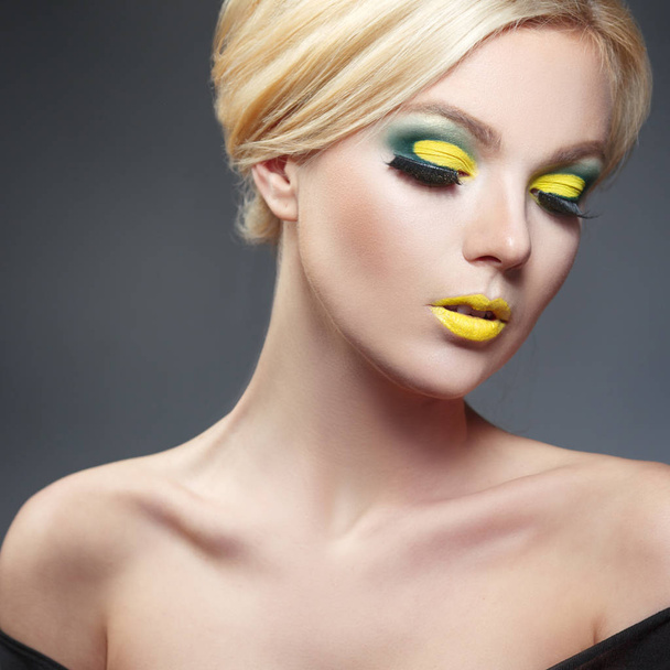 beauty portrait of beautiful blonde woman with yellow makeup looking down on gray background - Fotografie, Obrázek