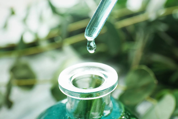 Dripping perfume oil into bottle on blurred background, closeup - Φωτογραφία, εικόνα