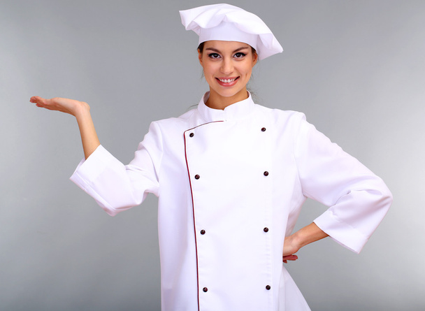 Portrait of young woman chef on grey background - Foto, Imagem