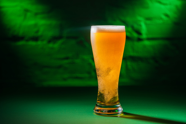 primer plano vista de vidrio con cerveza en luz verde, santo patricks concepto de día
 - Foto, Imagen