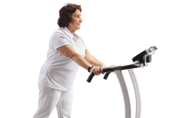 Mature woman walking on a treadmill isolated on white background - Zdjęcie, obraz