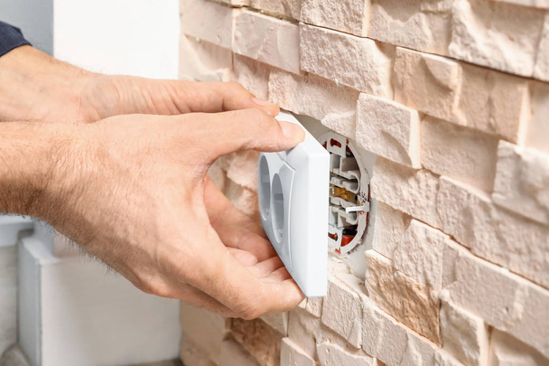 Electrician repairing socket on brick wall - Foto, Imagem