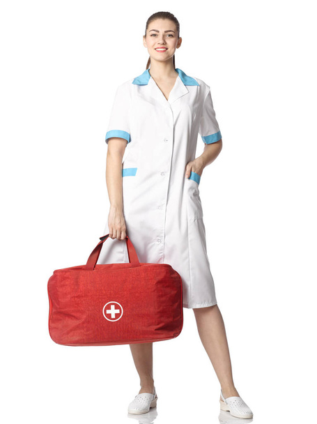 Beautiful nurse girl in suit with red bag and white cross. - Foto, imagen