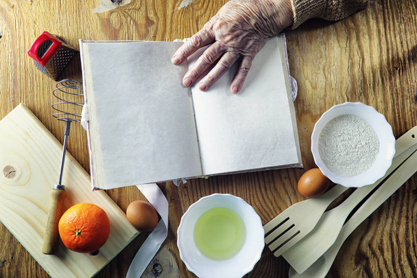 Βιβλίο ανοιχτό συνταγή στα χέρια του μια ηλικιωμένη γυναίκα - Φωτογραφία, εικόνα