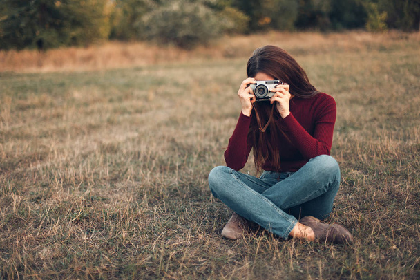 young woman sitting and taking photo on field - 写真・画像