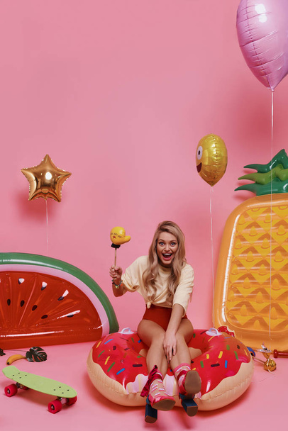 blonde young woman in red swimwear sitting on donut inflatable pool ring and laughing  - Φωτογραφία, εικόνα