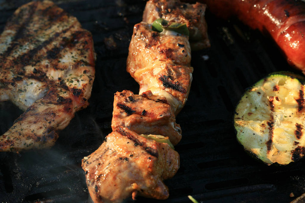 A set of meats baked on the grill during a family picnic in free time. Summer relaxation in the open air. - Photo, Image