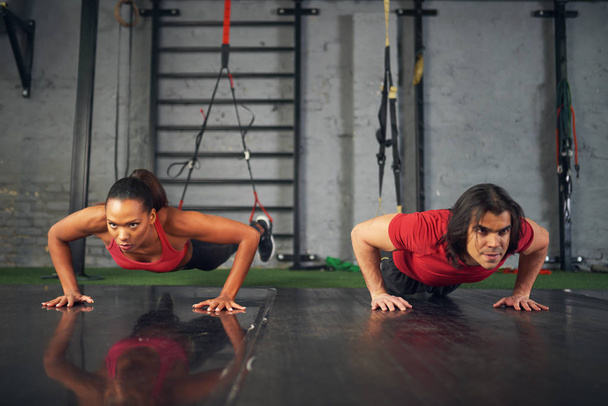 Young mixed race female and male athletes training in gym with sport equipment - Photo, Image