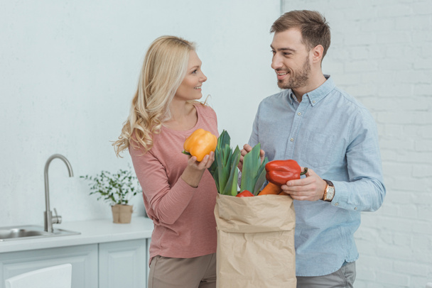 retrato de hijo y madre crecidos con bolsa de papel llena de verduras frescas para la cena en casa
 - Foto, Imagen