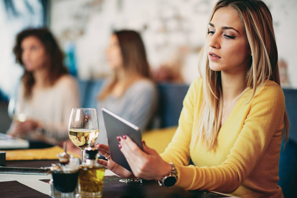Молода біла жінка використовує планшет, сидячи в кафе і штовхаючи
 - Фото, зображення