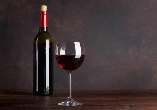 Red wine bottle and glass in front of blackboard wall. With copy space - Foto, afbeelding