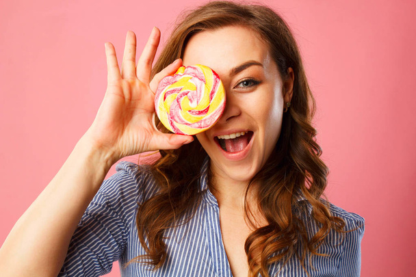 Portrait of a happy pretty girl holding sweet candy over pink ba - Foto, immagini
