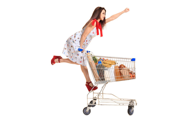 Frau mit Einkaufswagen voll mit Produkten auf weißem Hintergrund - Foto, Bild