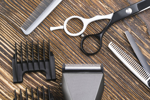 comb, scissors, razor and hair clipper lie on a brown wooden table - Photo, Image