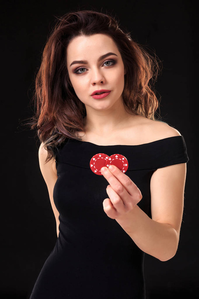 Smiling girl holding a gambling chips in her hands on black background. - Photo, Image