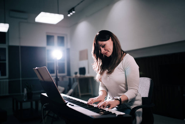Beautiful female composer playing piano. - Фото, зображення